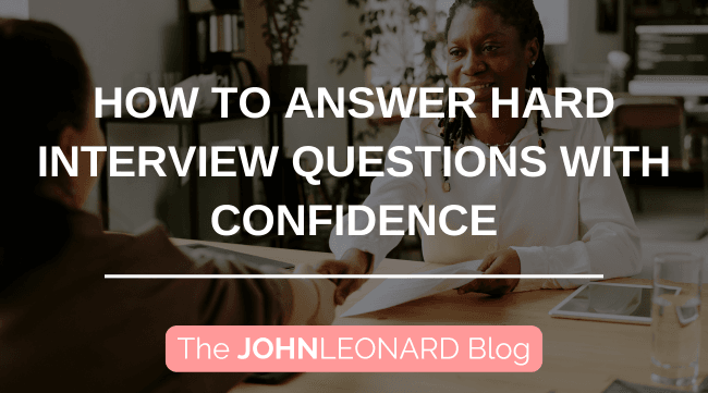 Blog graphic illustrating a formal job interview atmosphere, with two individuals seated across a desk shaking hands while examining documents. Prominent overlay text states “How to Answer Hard Interview Questions with Confidence” with JOHNLEONARD branding displayed at the bottom.